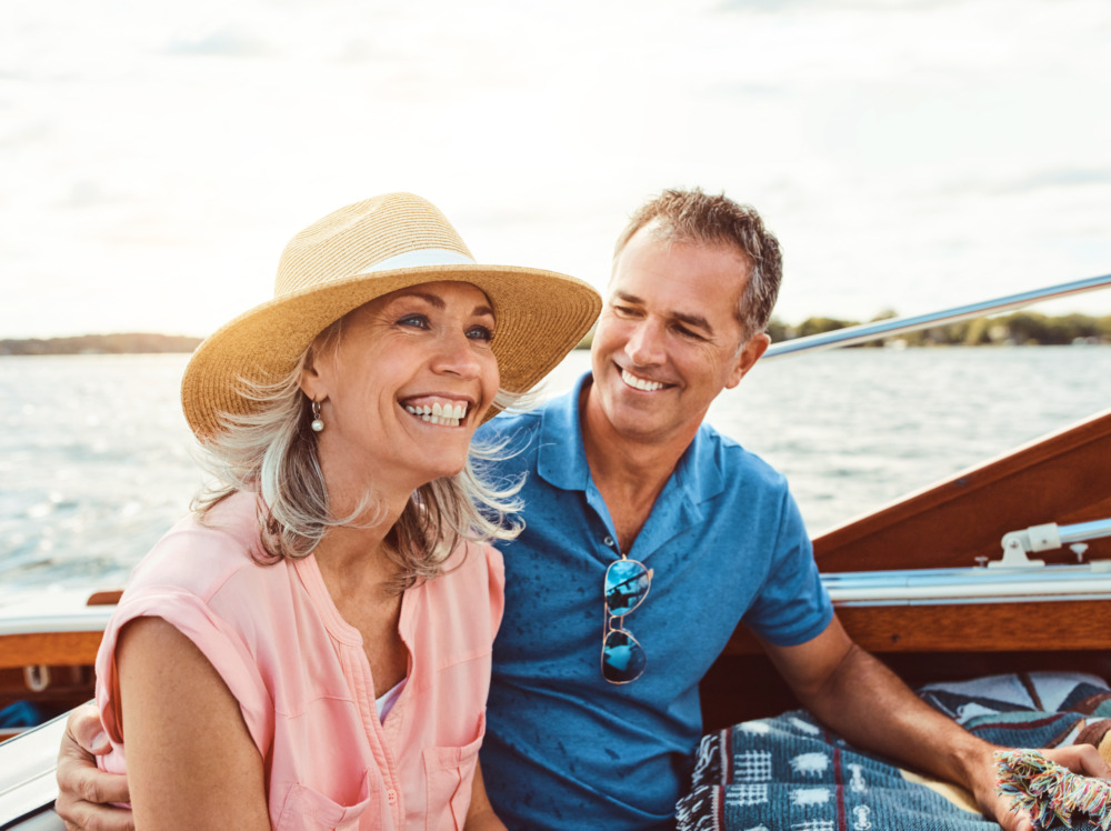Happy older couple, sitting on a boat out on the water and smiling together.