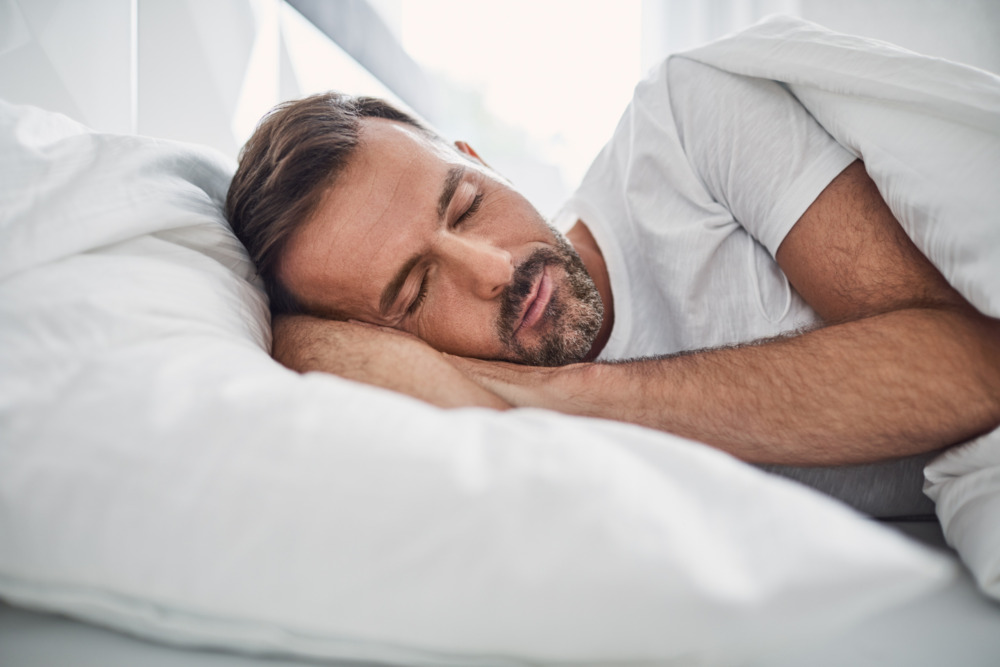 Side view of a man sleeping in his bed.