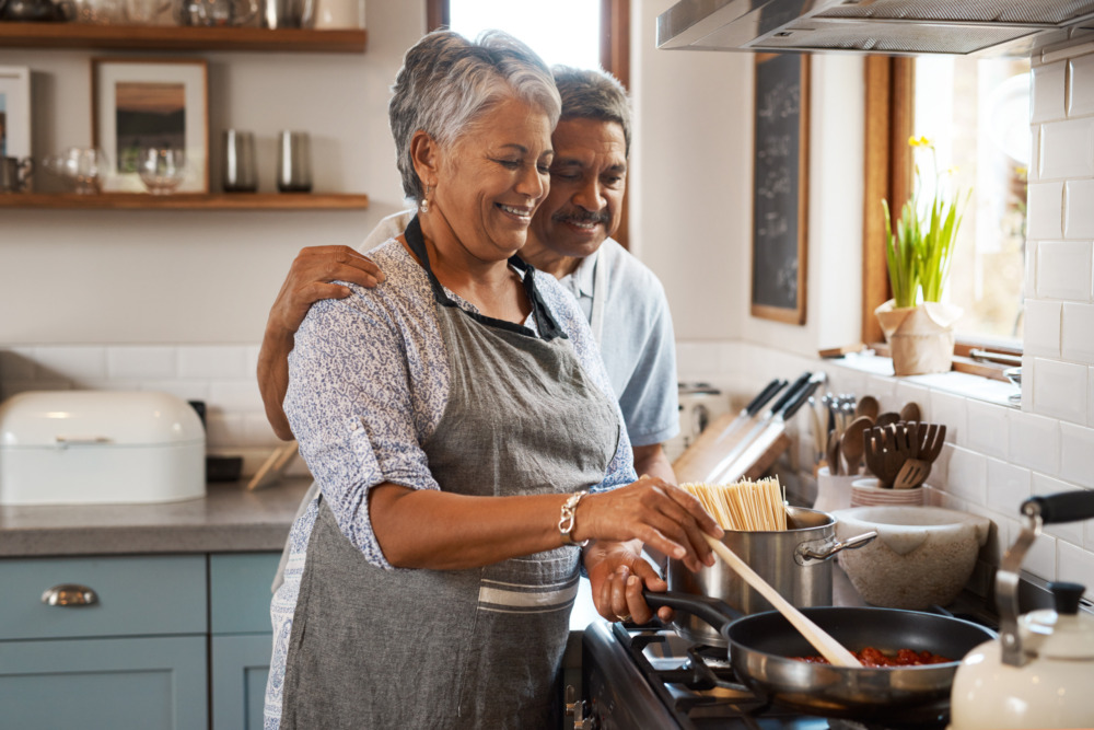 Older couple cooking together in the kitchen, in an embrace.