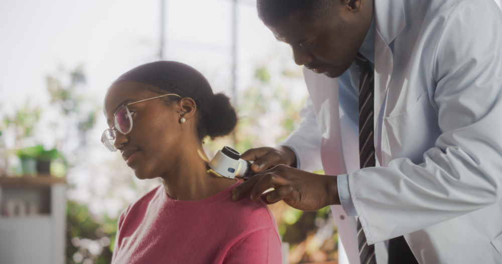 Woman having her neck inspected by a doctor with a microscope.